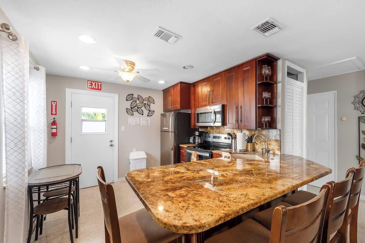 A kitchen with granite countertops, wooden cabinets, a stainless steel refrigerator, and a microwave.