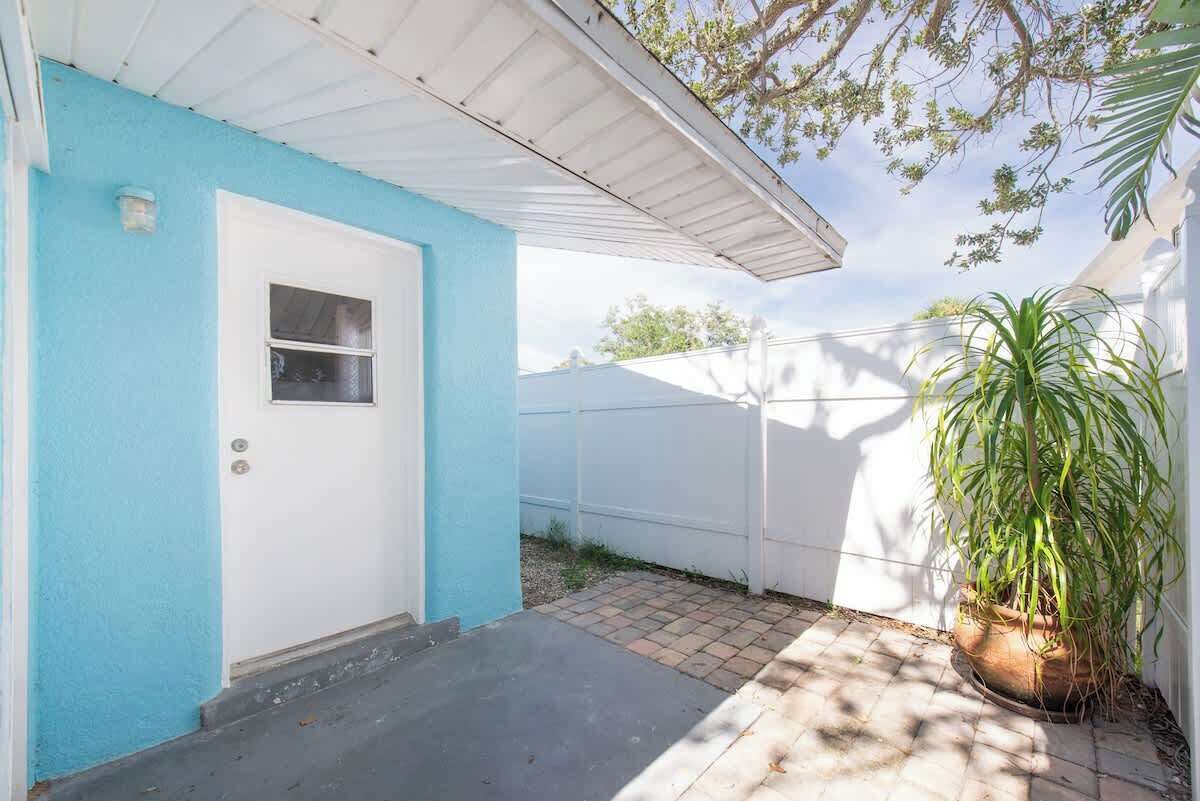 A house with a blue exterior, a white door, and a potted plant.