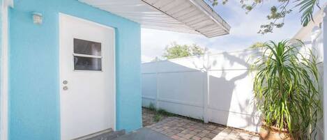 A house with a blue exterior, a white door, and a potted plant.