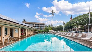 Una piscina con lettini e un edificio sullo sfondo con un balcone.