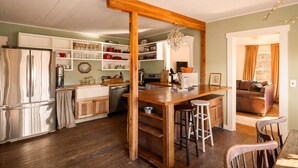 A kitchen with wooden beams, a central island, bar stools, a refrigerator, and a dining area with chairs. - Special Price! Charming 4-bedroom Farmhouse w/Hot Tub in Peaceful Wears Valley (Sevierville)