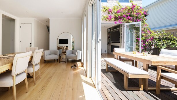 A modern interior with a wooden floor, a dining area with a table and chairs, a sofa, and a dog lying on the floor. - Pet Friendly - Evergreen by the Bay (Sandringham)