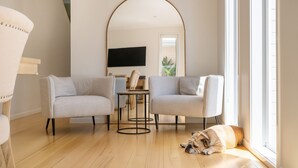 A modern living room with two sofas, a coffee table, and a dog lying on the floor. - Pet Friendly - Evergreen by the Bay (Sandringham)