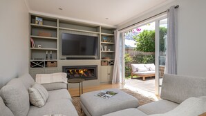 A living room with a fireplace, a television, and a sofa. - Pet Friendly - Evergreen by the Bay (Sandringham)