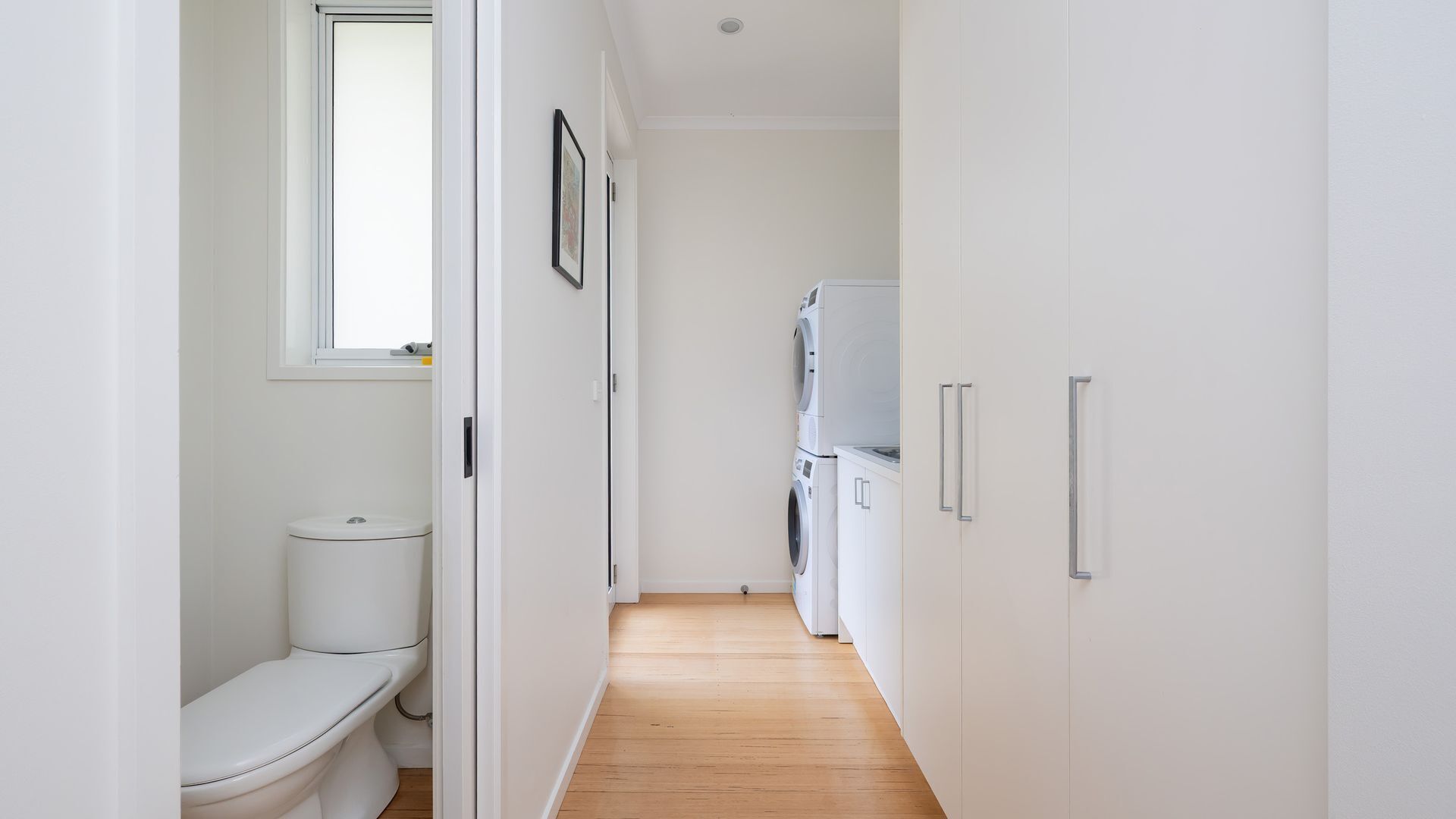 Ein schmaler Flur mit Toilette, Waschmaschine und Schrank.