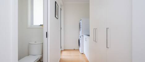 Ein schmaler Flur mit Toilette, Waschmaschine und Schrank.