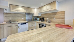 Une cuisine moderne avec des meubles en bois clair, des appareils en acier inoxydable et un four à micro-ondes encastré.