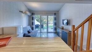 Un intérieur moderne avec une table à manger en bois, un canapé et un coin cuisine équipé de placards et d’un téléviseur.