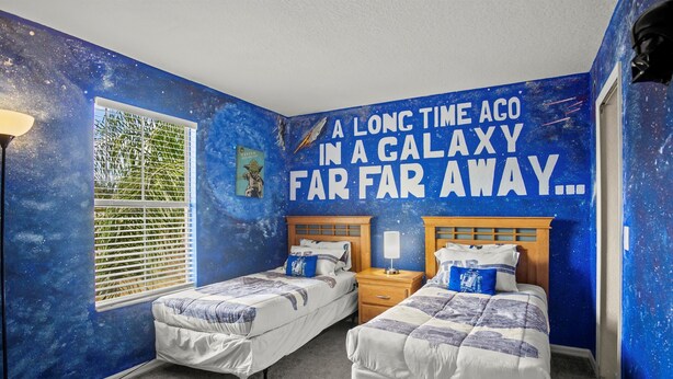 A bedroom with two beds, a window with blinds, a wall mural, and a nightstand with a lamp. - Resort Style Family Friendly 4bd Near Disney (Davenport)