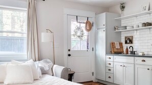Ein Schlafzimmer mit Bett, Nachttisch, Vorhängen am Fenster und Blick ins Freie.