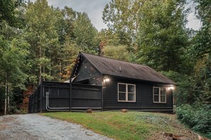 Une cabane avec une façade en bois sombre, un toit en pente et une allée gravillonnée.