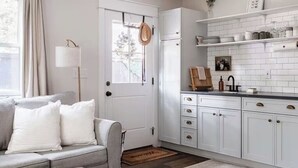 Eine moderne Küche mit weißen Schränken, einer schwarzen Arbeitsplatte und einem Essbereich mit einem Holztisch und einem Stuhl.