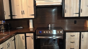 Eine Küche mit Holzausstattung, einem Edelstahlbackofen und einer Holz Arbeitsplatte.