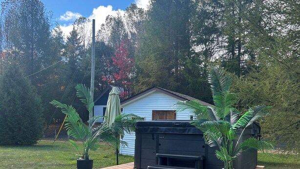 Ein Garten mit einer Holzterrasse, einem Grill und Pflanzen in Töpfen.