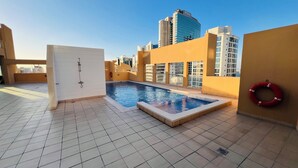 Un área de piscina en la azotea con suelo de baldosas, una puerta y un flotador.