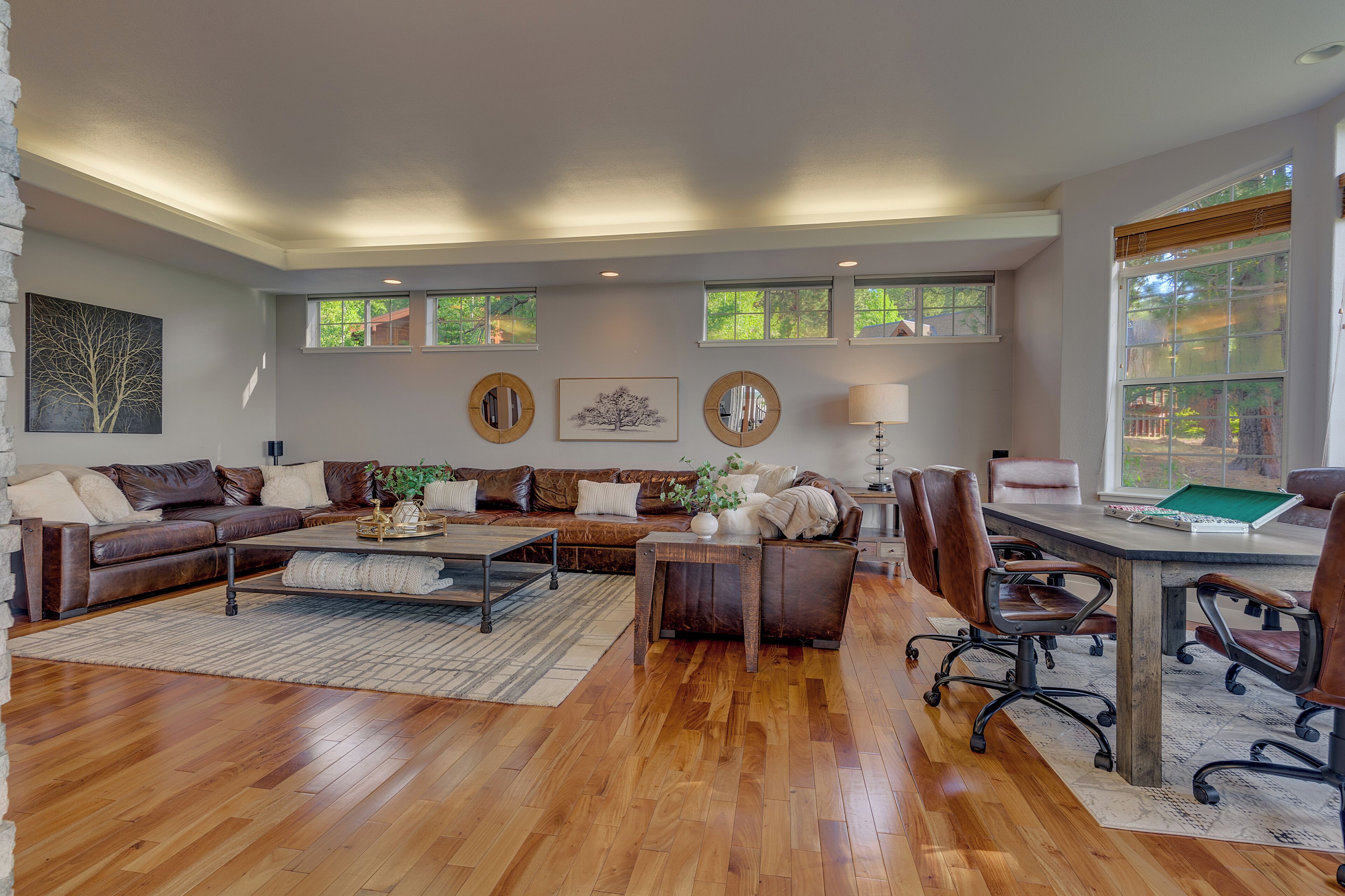 A spacious living room with a wooden floor, leather sofas, a coffee table, and a dining area with chairs and a table.