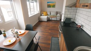 A modern kitchen with a dining area, a sofa, and a painting on the wall. - Serdica Tower View DT Parking Wi-Fi AC (Sofia)