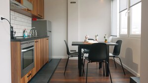 A modern kitchen with wooden cabinets, a built-in oven, and a dining area with a table and chairs. - Serdica Tower View DT Parking Wi-Fi AC (Sofia)