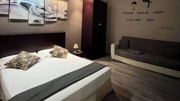 Una camera da letto moderna con un letto grande, un divano e decorazioni alle pareti.