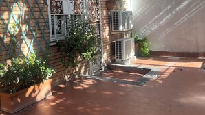 A courtyard with a brick wall, a metal gate, and a potted plant. - ciak Beb Cinecittà a 10 minutes to Rome centre (Roma)