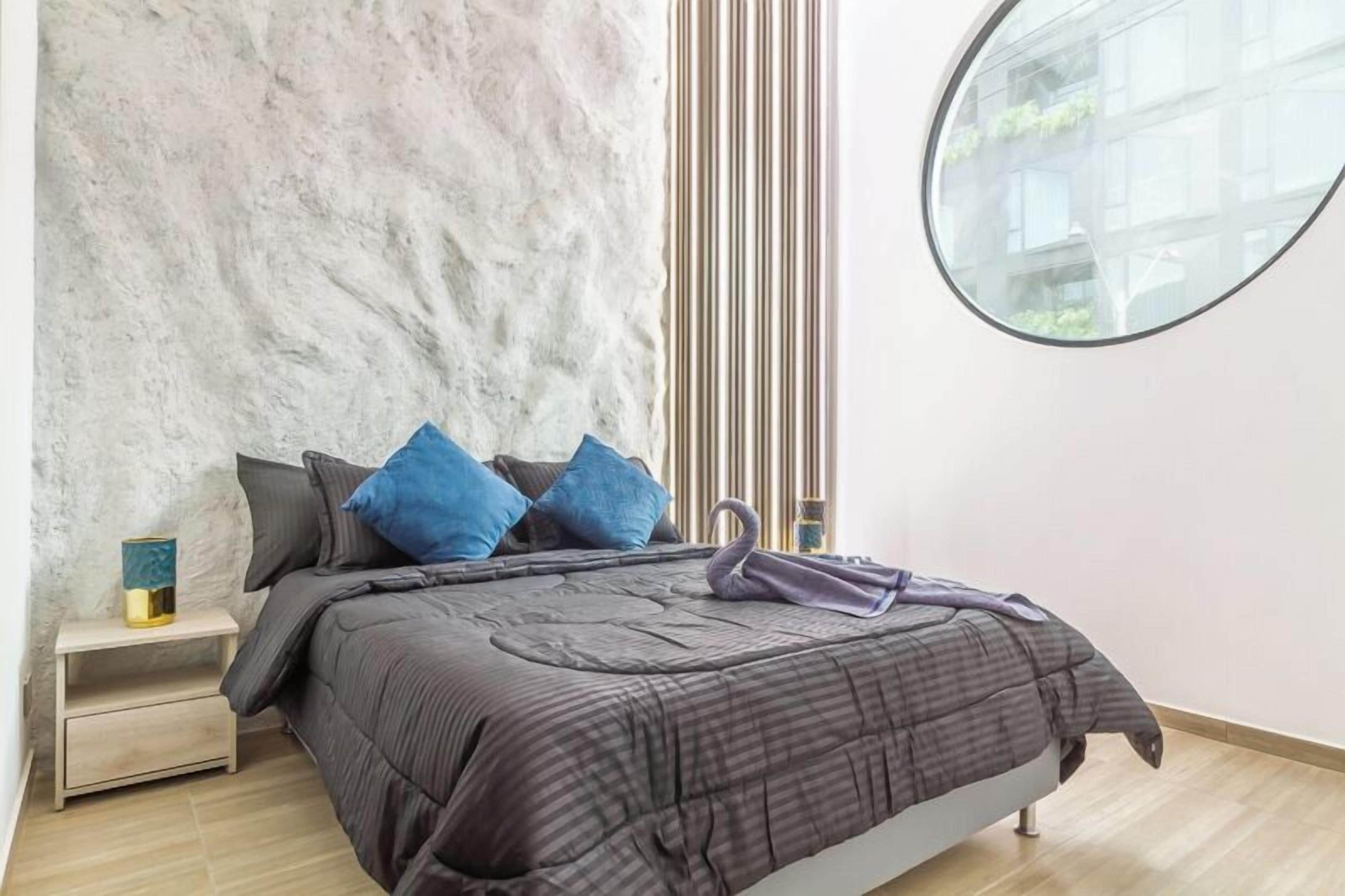 A bedroom with a bed, a nightstand, a window, and a wall with vertical lines.
