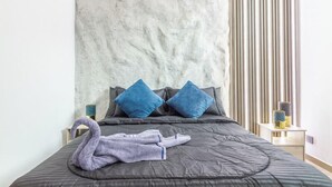 A bed with a grey quilt, two blue pillows, and a purple towel. - 6BR w Jacuzzi  Private Baths Lleras (Medellín)