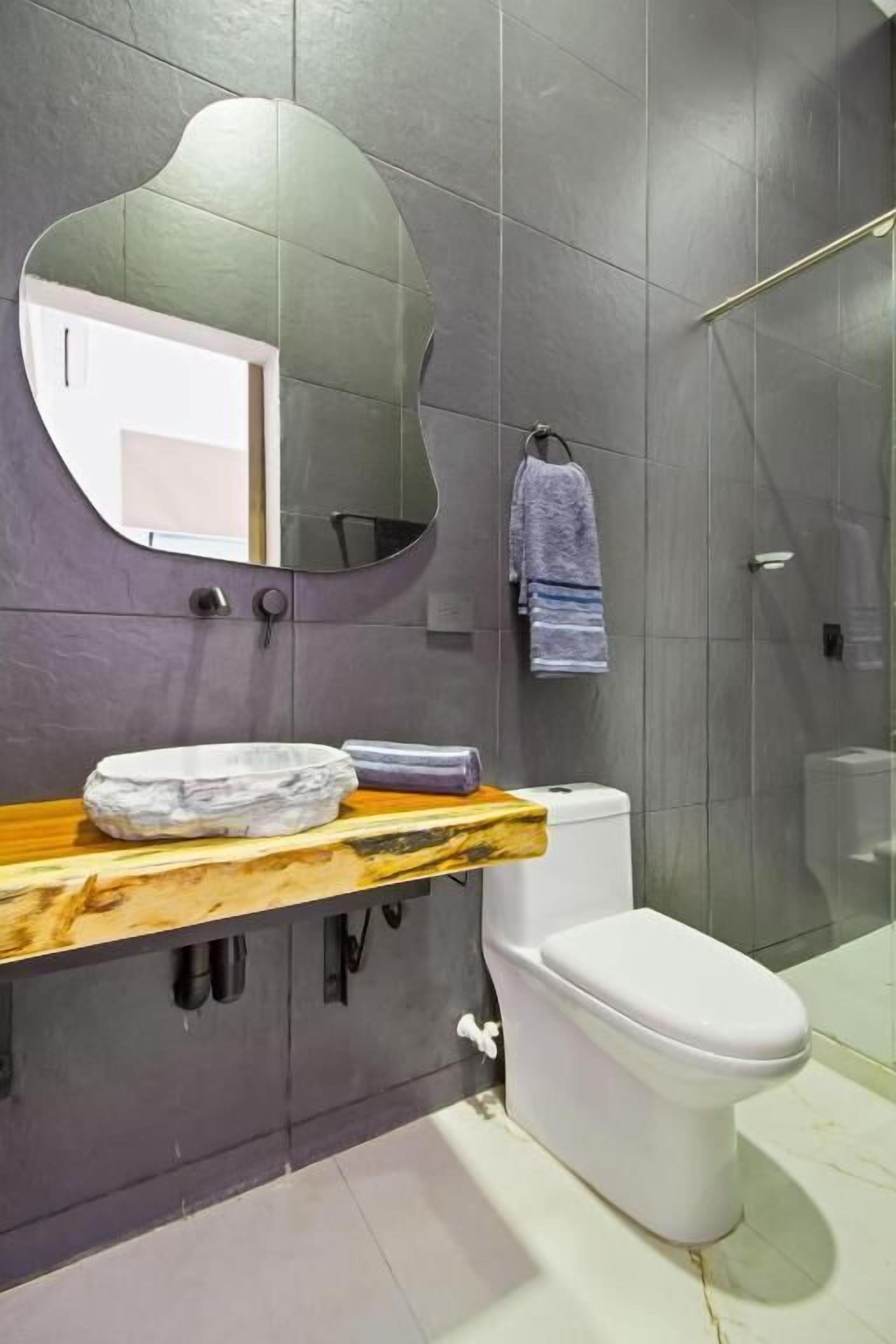 A modern bathroom with a marble vanity, a white toilet, and a large mirror.