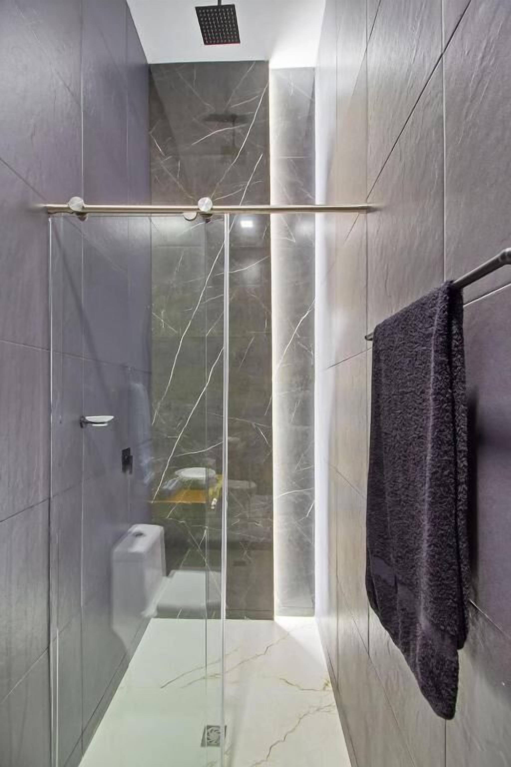 Un baño moderno con cabina de ducha de vidrio, paredes de mármol y un perchero para toallas.