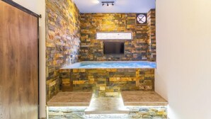 A spa area with a stone wall, a hot tub, and a mounted TV. - 6BR w Jacuzzi  Private Baths Lleras (Medellín)