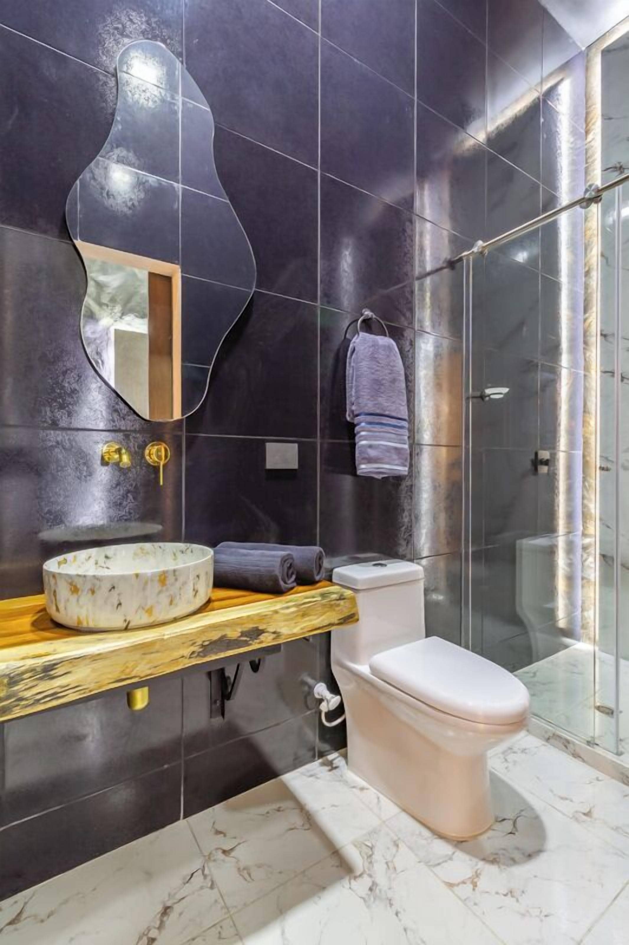 A modern bathroom with a marble sink, a toilet, and a glass shower enclosure.