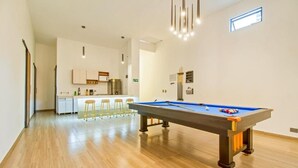 A modern living room with a pool table, wooden flooring, and a kitchen area in the background. - 6BR w Jacuzzi  Private Baths Lleras (Medellín)