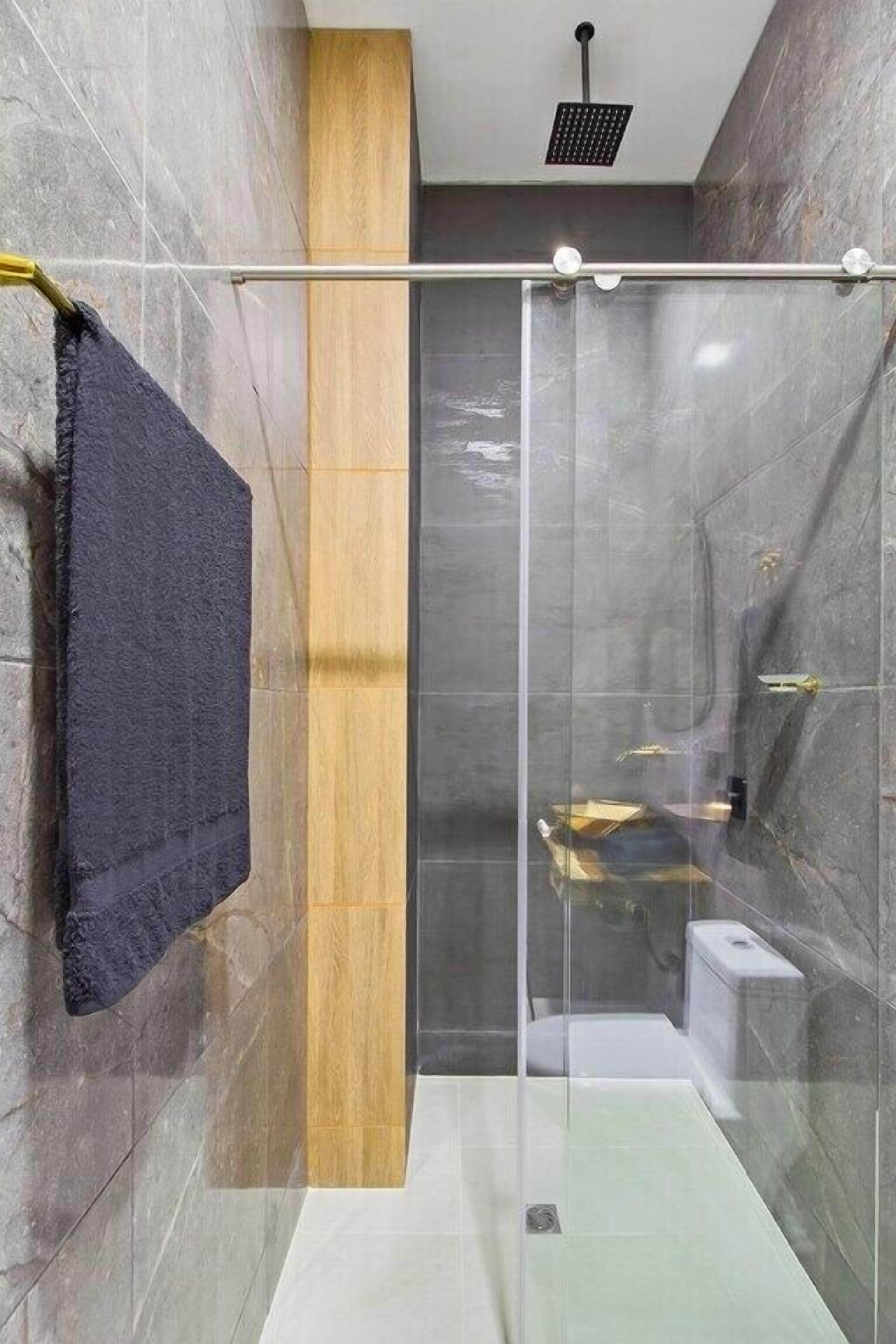 A modern bathroom with a glass-enclosed shower, a wooden accent wall, and a towel rack.