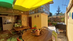 A wooden table with chairs and a yellow umbrella, surrounded by potted plants and a small garden area. - House for 12 people minutes from the beach (Coquimbo)