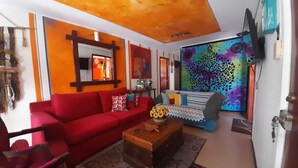 A living room with a red sofa, a wooden coffee table, and a colorful wall mural. - House for 12 people minutes from the beach (Coquimbo)