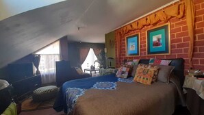 A bedroom with a sloped ceiling, a bed with multiple pillows, a nightstand, and a window with curtains. - House for 12 people minutes from the beach (Coquimbo)