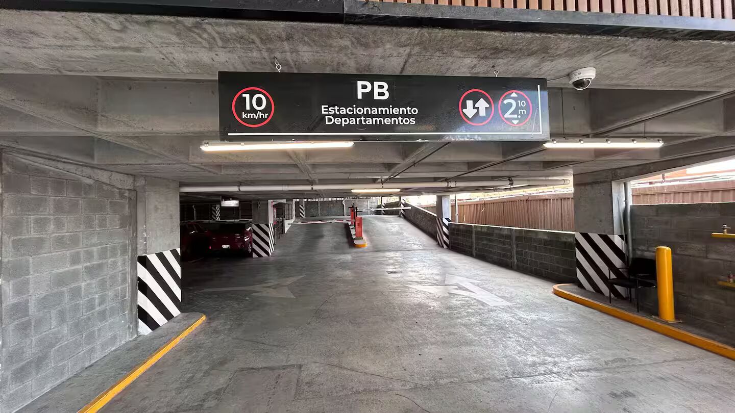 Een parkeergarage met een bord waarop een snelheidslimiet van 10 km/u en een maximale hoogte van 2 meter aangegeven is.
