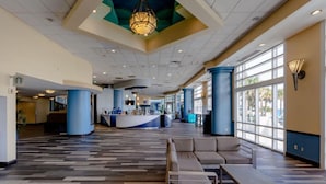 A spacious lobby with a reception desk, seating area, and large windows. - Family-Friendly 2BR Suite at Ocean Walk - Beach & Pools Await (Daytona Beach)