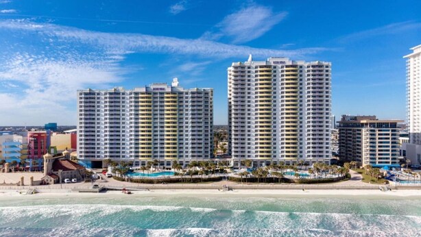A beachfront hotel with multiple high-rise buildings, a pool area, and a beach. - Family-Friendly 2BR Suite at Ocean Walk - Beach & Pools Await (Daytona Beach)