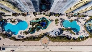 An aerial view of a resort with multiple swimming pools, a beach area, and high-rise buildings. - Family-Friendly 2BR Suite at Ocean Walk - Beach & Pools Await (Daytona Beach)