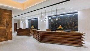 A reception area with a wooden reception desk, a large wall with a leaf pattern, and hanging pendant lights. - Waikiki 1BR at Grand Islander – Full Kitchen, Beach & Resort Fun at Hilton Villa (Honolulu)
