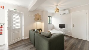 Una sala de estar moderna con un sofá verde, una mesa redonda de centro y un televisor de pantalla plana.
