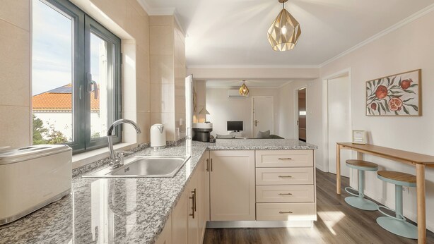Una cocina moderna con encimera de granito, pileta de acero inoxidable y horno integrado. Hay una ventana que proporciona luz natural y vistas al exterior.