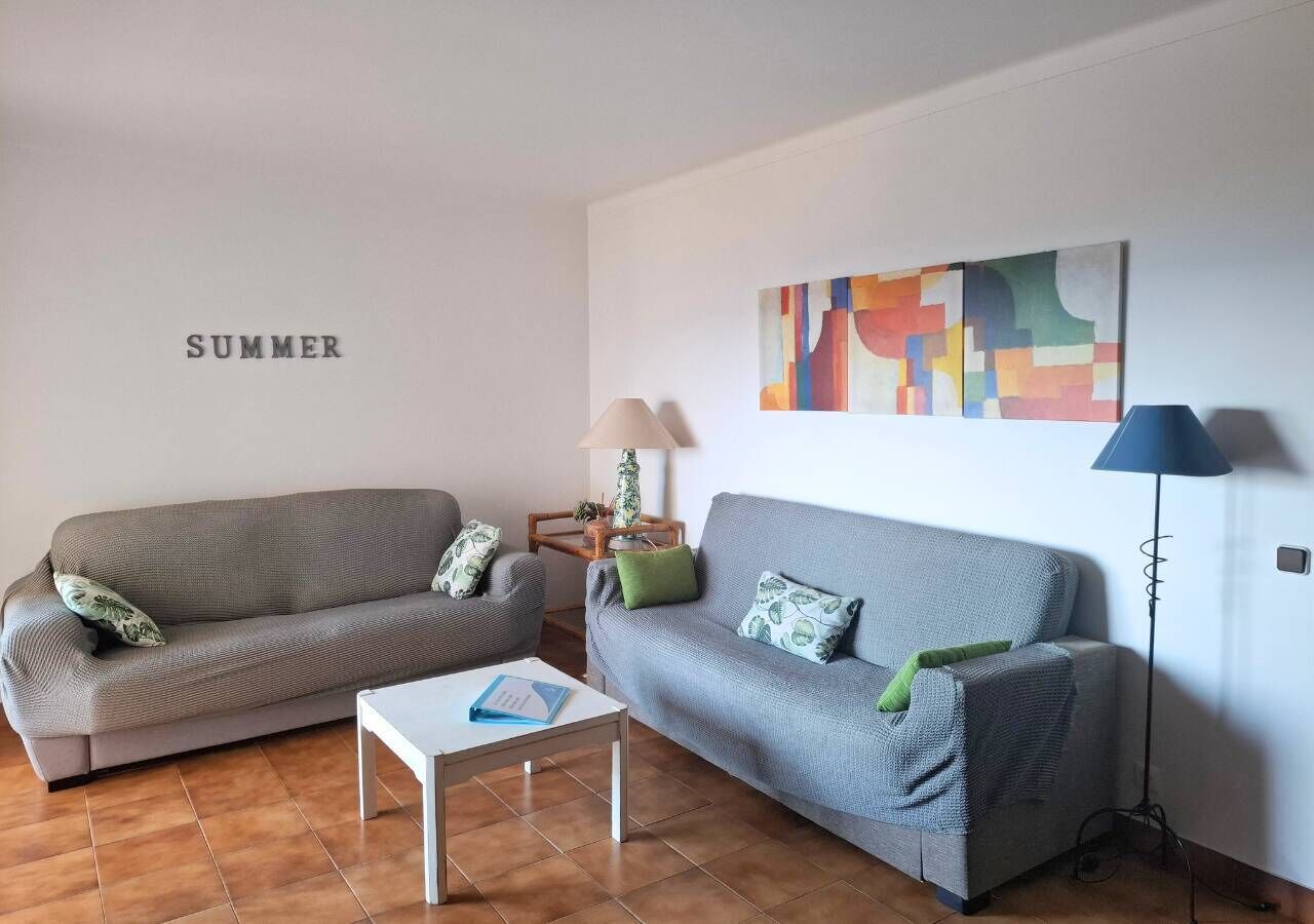 Ein Wohnzimmer mit zwei Sofas, einem Couchtisch, einer Lampe und einem farbenfrohen abstrakten Gemälde an der Wand.