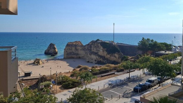 A coastal view with a beach, rocky formations, and a clear sky. - PRAIA DA ROCHA - ATLANTICO IV (Portimão)