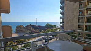 A balcony with a view of the beach and ocean, featuring a table and chairs. - PRAIA DA ROCHA - ATLANTICO IV (Portimão)