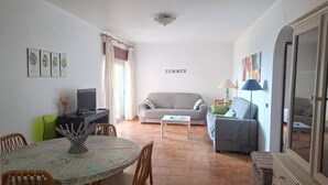 A living room with a dining table, sofa, and TV. - PRAIA DA ROCHA - ATLANTICO IV (Portimão)