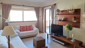 A modern living room with a sofa, TV, and decorative items. - PRAIA DA ROCHA- CASA DA PRAIA 702 (Portimão)