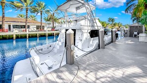 Eine Yacht liegt in einer Marina vor Anker, mit einem Holldeck, einem überdachten Bereich und einem Pool im Hintergrund.