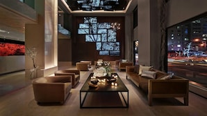 A modern lounge with sofas, a coffee table, and a large window with city lights visible outside.
