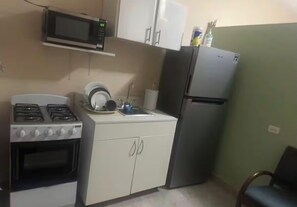 A compact kitchen with a gas stove, microwave, refrigerator, and white cabinets. - Cozy and nice apartment on The heart of San Juan (San Juan)